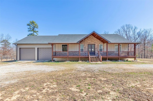 view of front of house with roof with shingles, an attached garage, covered porch, french doors, and board and batten siding