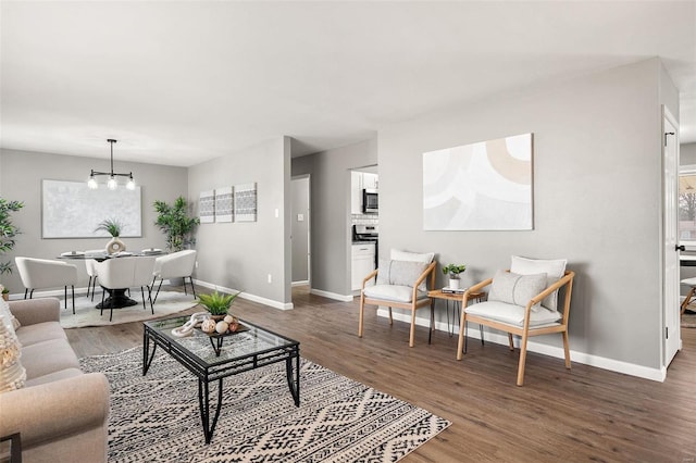 living room with baseboards, an inviting chandelier, and wood finished floors