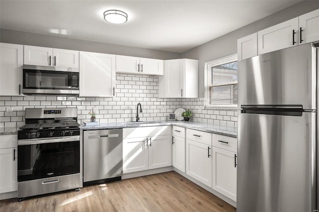 kitchen featuring a sink, appliances with stainless steel finishes, light wood-style flooring, and white cabinetry