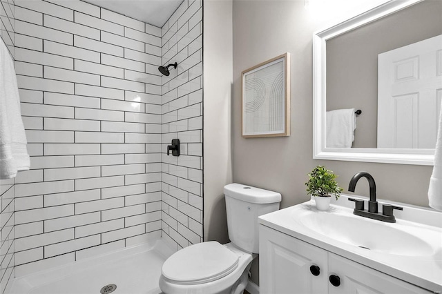 bathroom featuring tiled shower, toilet, and vanity