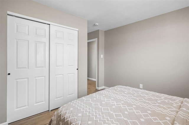 bedroom featuring a closet, baseboards, and wood finished floors