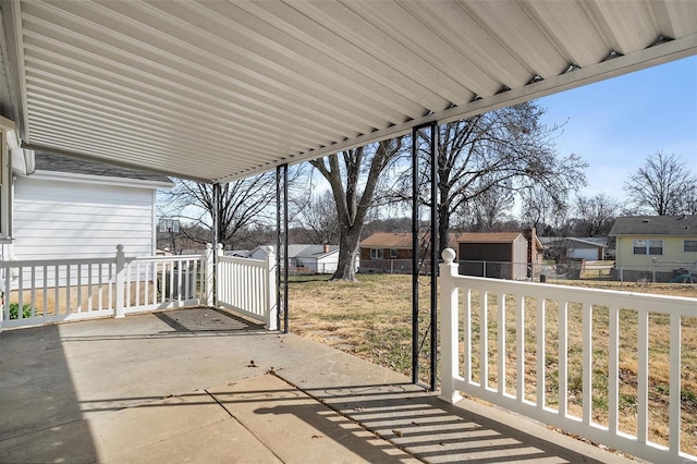 view of patio / terrace with an outbuilding, fence, and a residential view