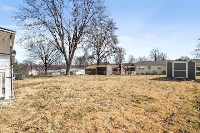 view of yard with a shed, central AC unit, an outdoor structure, and fence