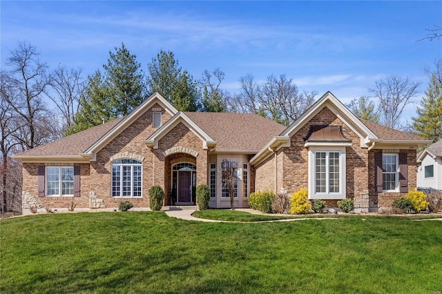 ranch-style home featuring brick siding, a front yard, and roof with shingles