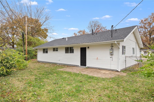 rear view of house with a lawn, a patio, and roof with shingles