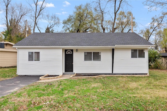 single story home featuring aphalt driveway, a front lawn, and a shingled roof