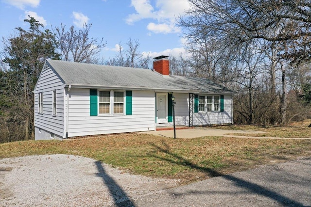 view of front of property with driveway, roof with shingles, and a chimney