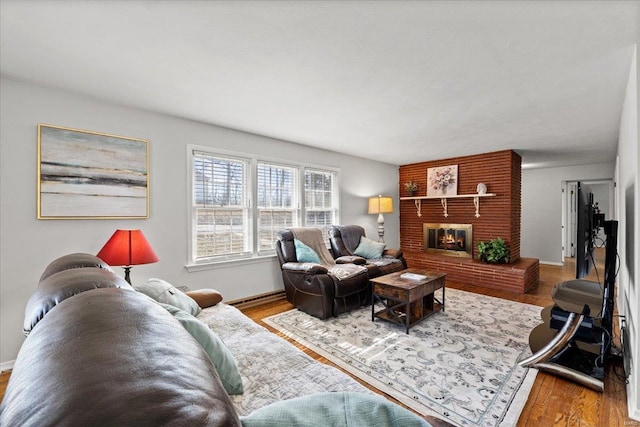 living room with a baseboard heating unit, baseboards, a brick fireplace, and wood finished floors