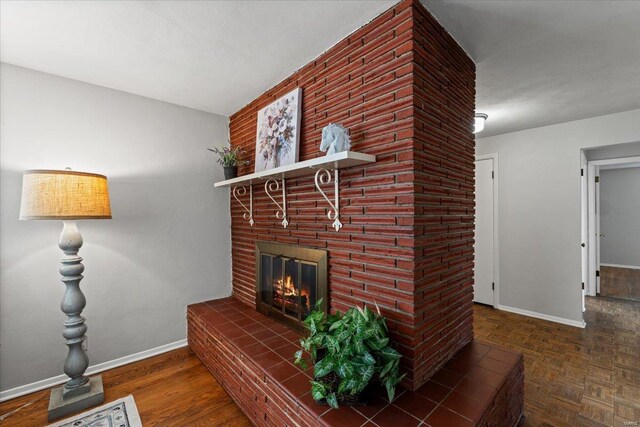 living area with a brick fireplace, parquet flooring, and baseboards