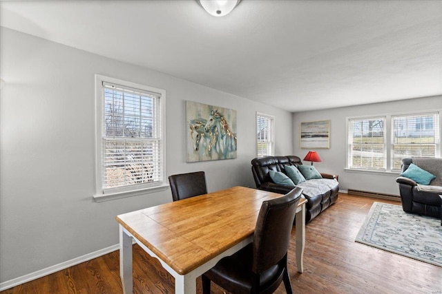 dining space featuring a baseboard radiator, baseboards, and dark wood-style flooring