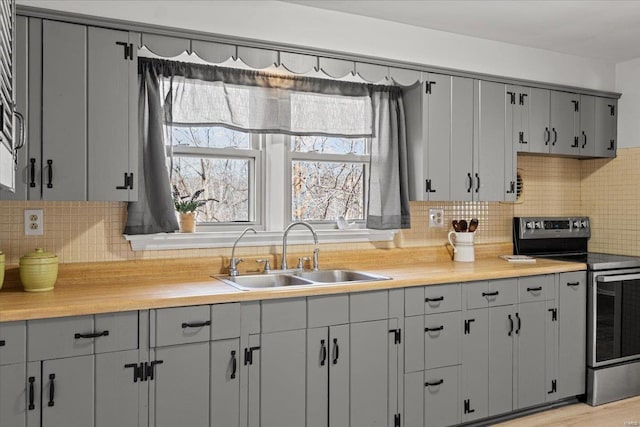 kitchen with a sink, stainless steel range with electric stovetop, gray cabinetry, and light countertops