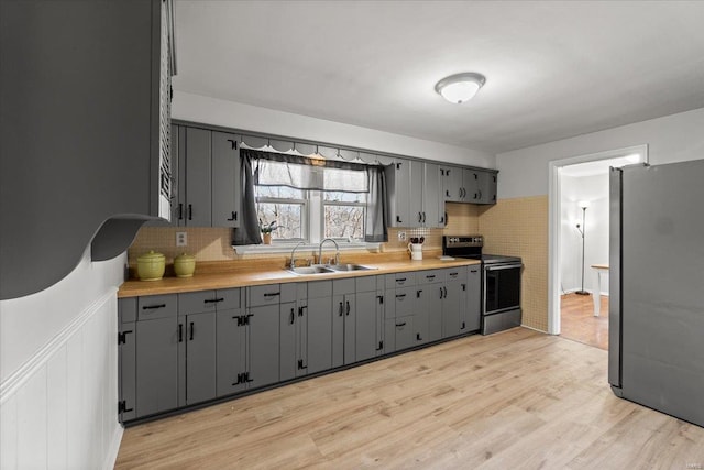 kitchen with a sink, light wood-style floors, gray cabinets, and stainless steel appliances