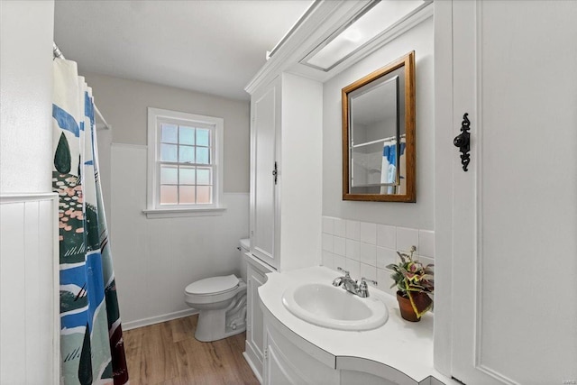 bathroom featuring a wainscoted wall, toilet, a shower with curtain, wood finished floors, and vanity