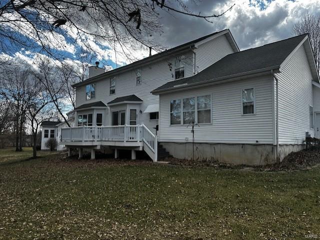 back of house featuring a deck, a yard, and a chimney