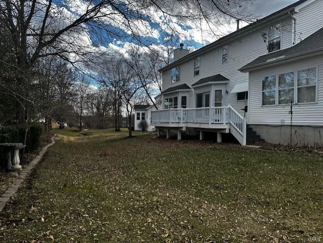 back of house with a wooden deck, a yard, and a chimney