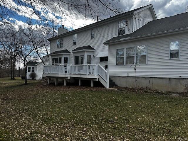 back of house with a deck, a lawn, and a chimney