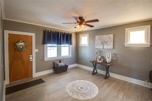 foyer entrance with baseboards, wood finished floors, ornamental molding, and a ceiling fan