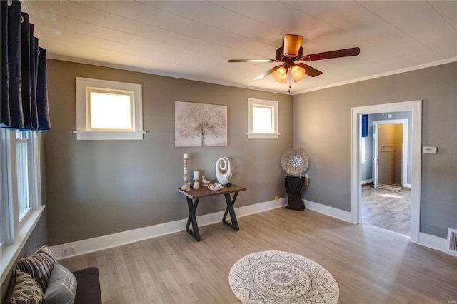 interior space with visible vents, light wood-type flooring, crown molding, and baseboards