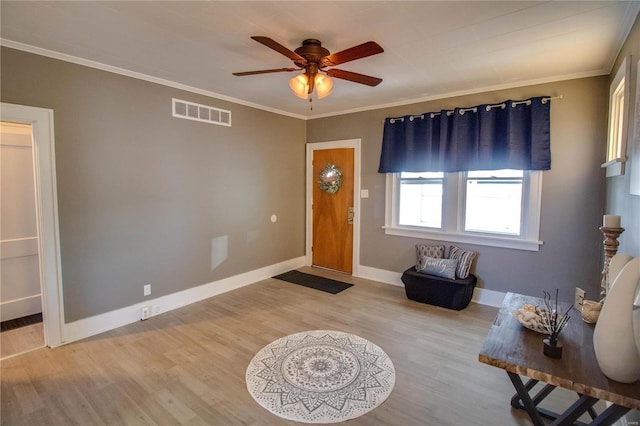 foyer entrance with visible vents, wood finished floors, crown molding, baseboards, and ceiling fan