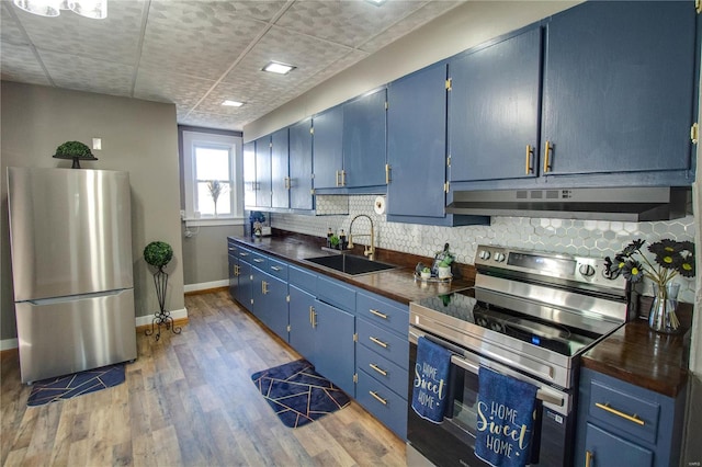 kitchen featuring a sink, blue cabinetry, under cabinet range hood, and stainless steel appliances