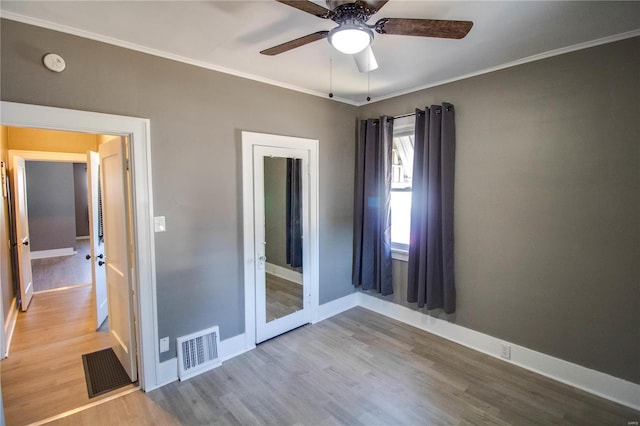 unfurnished room with visible vents, baseboards, ceiling fan, ornamental molding, and wood finished floors