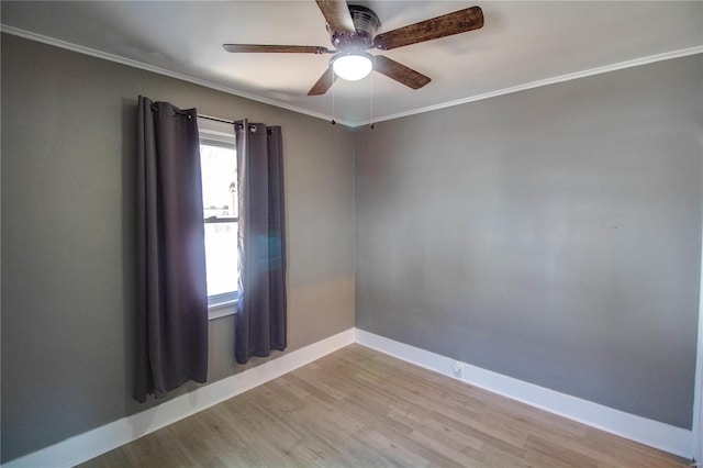 empty room featuring a ceiling fan, crown molding, wood finished floors, and baseboards