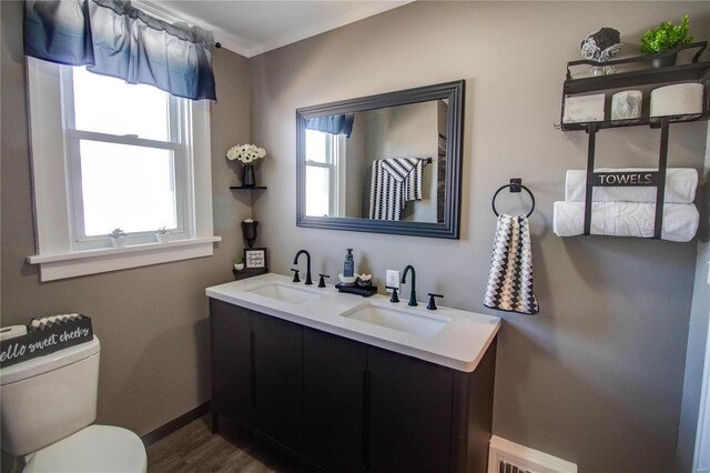 bathroom with double vanity, visible vents, toilet, and a sink