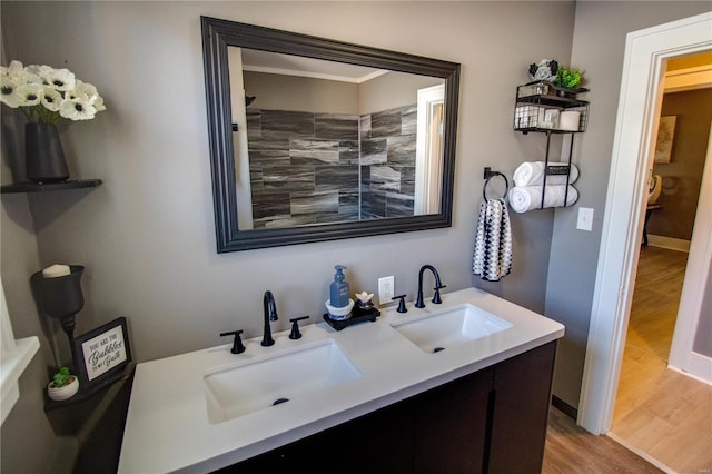 full bath with double vanity, wood finished floors, baseboards, and a sink