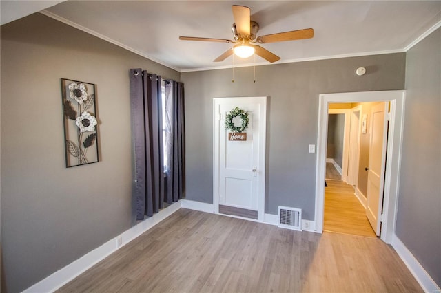 foyer entrance featuring light wood finished floors, visible vents, baseboards, and ornamental molding