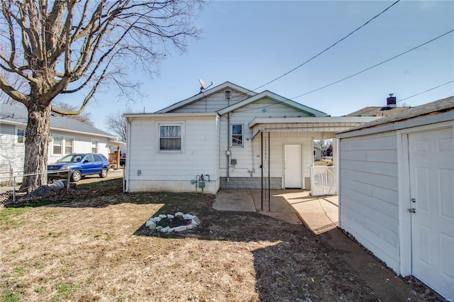 back of property with an outbuilding, a yard, and fence