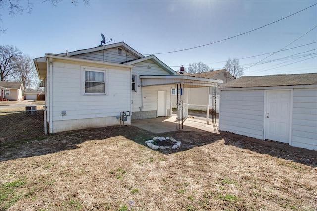 rear view of property with an outdoor structure, a patio, and fence