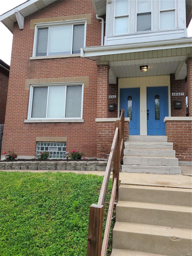 entrance to property with brick siding and a porch