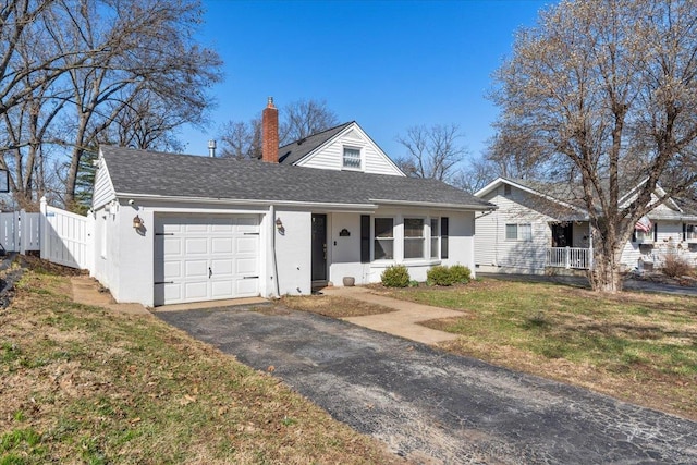 view of front of house with a shingled roof, fence, aphalt driveway, a chimney, and an attached garage