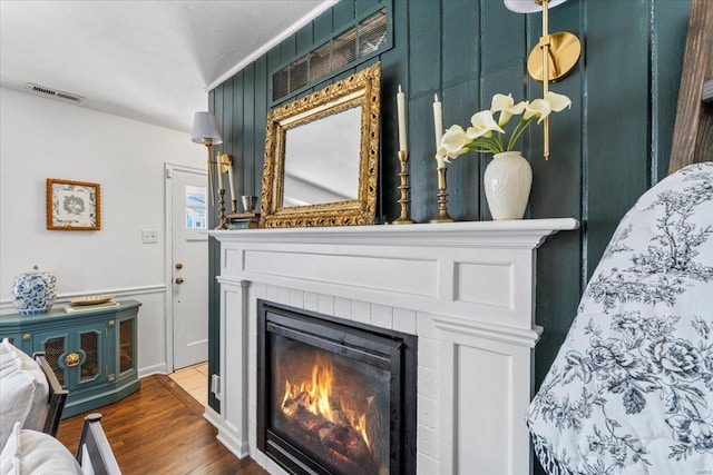 interior details with wood finished floors, visible vents, and a tile fireplace