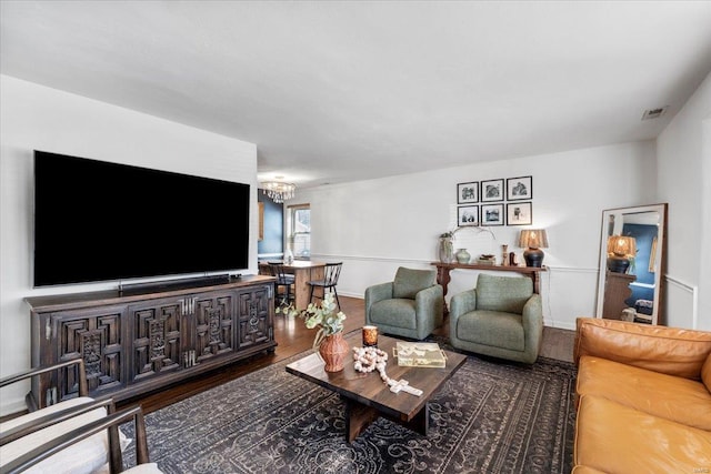 living area featuring visible vents, baseboards, a notable chandelier, and wood finished floors