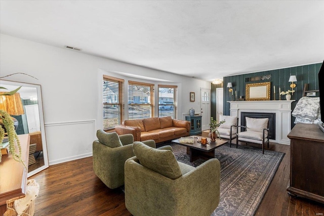 living room featuring wood finished floors, a fireplace, visible vents, and baseboards