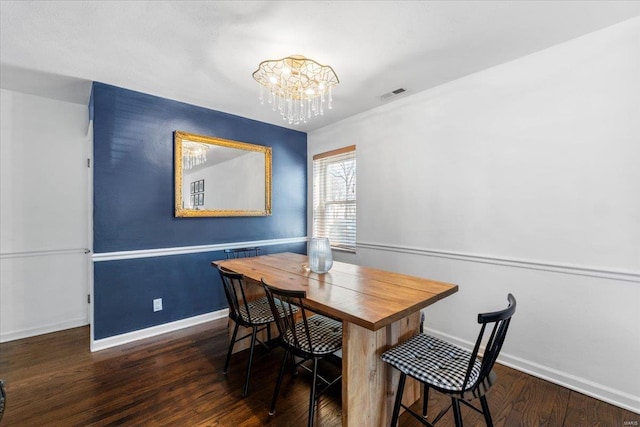 dining space with visible vents, baseboards, an inviting chandelier, and wood finished floors