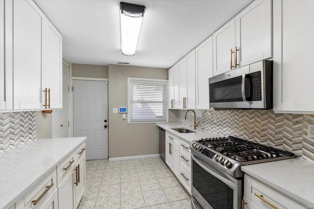 kitchen with backsplash, white cabinetry, stainless steel appliances, and a sink