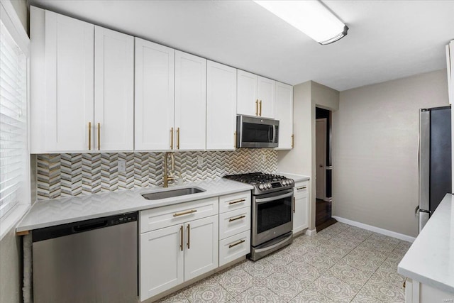 kitchen featuring tasteful backsplash, baseboards, appliances with stainless steel finishes, white cabinetry, and a sink