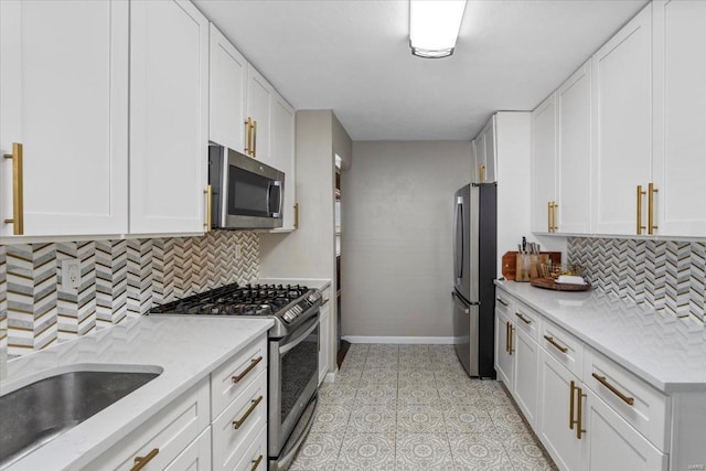 kitchen featuring white cabinets, backsplash, baseboards, and appliances with stainless steel finishes