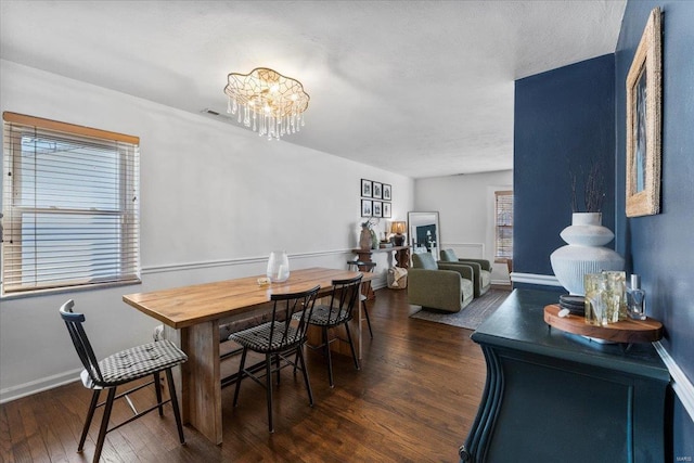 dining area featuring baseboards, a chandelier, and dark wood-style flooring