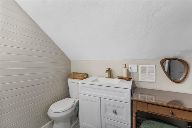 bathroom with toilet, vanity, and vaulted ceiling