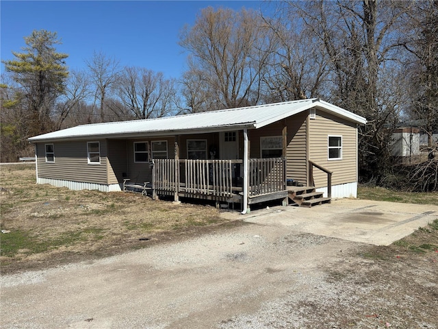 manufactured / mobile home featuring metal roof, a porch, and driveway