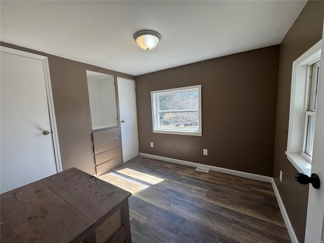 unfurnished bedroom featuring visible vents, baseboards, and wood finished floors