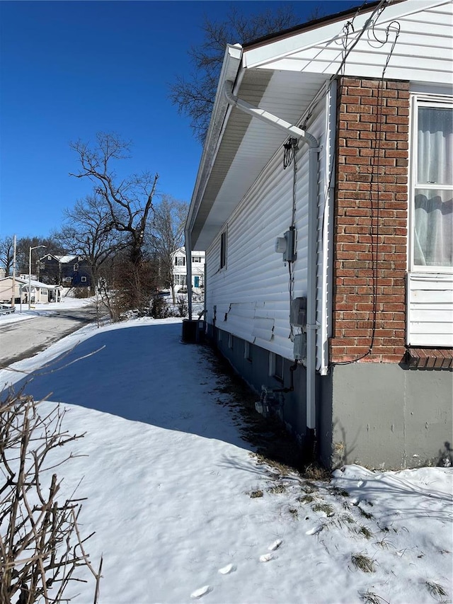 view of snowy exterior featuring brick siding