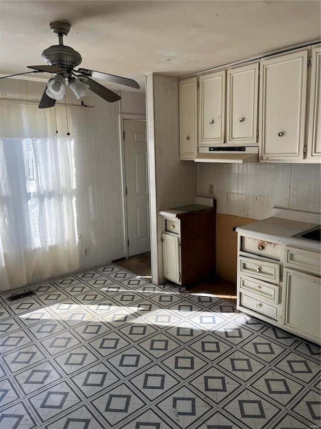 kitchen featuring under cabinet range hood, light floors, a ceiling fan, and light countertops