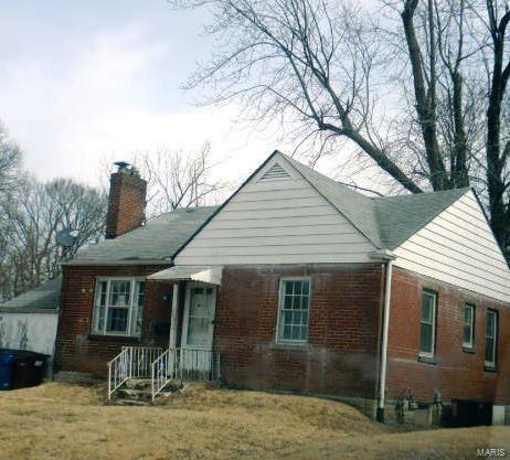 view of front of home with a front yard, brick siding, and a chimney