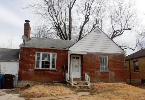 bungalow-style house featuring brick siding and a chimney