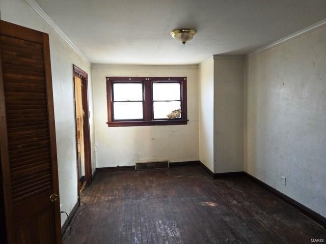 spare room with visible vents, baseboards, hardwood / wood-style floors, and crown molding