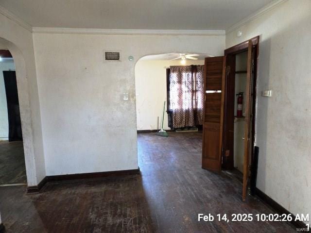 spare room with arched walkways, dark wood-style floors, and crown molding